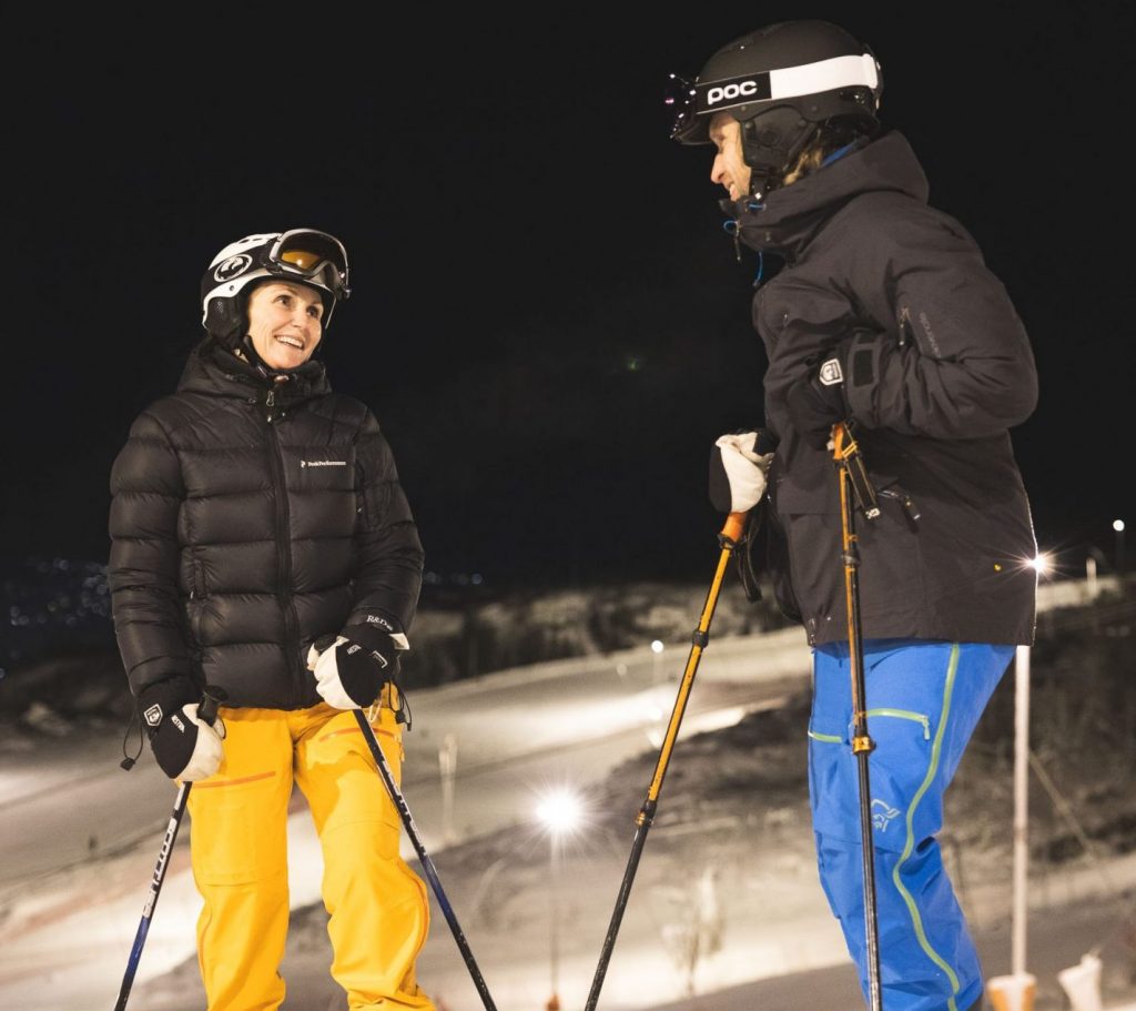 Kvinne og mann står i skibakke. Foto.